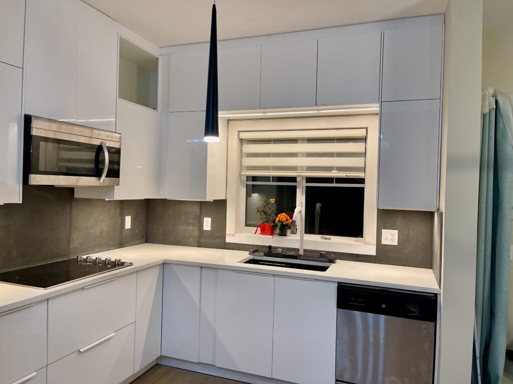 Renovated kitchen with white cabinets, pendant lighting and stainless appliances by Dandy RenoWork