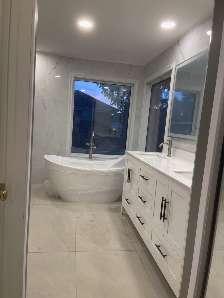 Renovated bathroom with marble tile walls and glass shower by Dandy RenoWork
