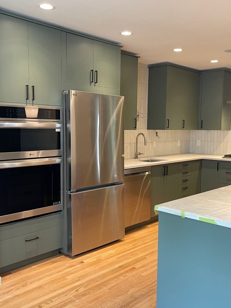 Renovated kitchen with sage green cabinets and stainless appliances by Dandy RenoWork